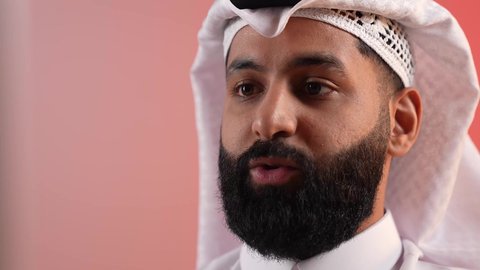 اجراء مقابلة عمل، التواصل مع الأهل والاصدقاء، الاهتمام بالمظهر الخارجي، مفهوم الأناقة والوسامة، بورتريه مقرب لرجل عربي خليجي سعودي يرتدي الغترة والعقال، شاب قطري يقوم بالتحدث إلى شخص ما بإيماءات الثقة بالنفس، خلفية ملونة