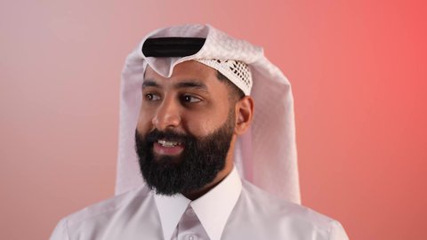 Concern about one's appearance, the concept of elegance and handsomeness, a close-up portrait of a Saudi Arabian Gulf man wearing a ghutra and agal, a Qatari young man looking at something with gestures of self-confidence, a colorful background