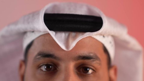 مفهوم الأناقة والوسامة، الاهتمام بالمظهر الخارجي، بورتريه مقرب لرجل عربي خليجي سعودي يرتدي الغترة والعقال، شاب قطري ينظر إلى الكاميرا بإيماءات الثقة بالنفس، خلفية ملونة