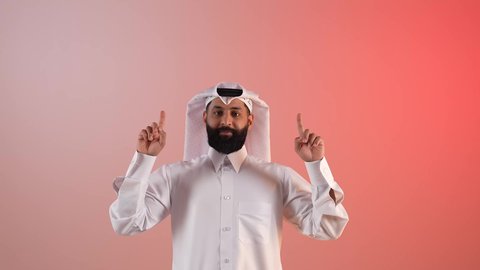 الأناقة والاهتمام بالمظهر الخارجي، تأكيد حدوث شيء هذه اللحظة, حركات تدل على هذا المكان (هنا)، شاب سعودي يقوم بتحديد موقع معين، بورتريه لرجل عربي خليجي قطري يرتدي الثوب التقليدي والغترة يشير بإصابع السبابة نحو الأعلى, النظر إلى الكاميرا بايماءات السرور، خلفية ملونة