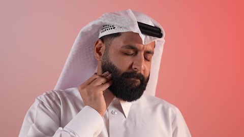 مشاكل التهاب اللثة وتسوس الأسنان, شاب سعودي يشعر بالتعب والارهاق، بورتريه مقرب لرجل عربي خليجي قطري يرتدي الثوب التقليدي والغتره يضع يده على فمه بإيماءات الانزعاج والألم الشديد، خلفية ملونة