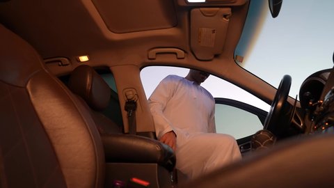الاستعداد لركوب السيارة، مفهوم القيادة الآمنة, رجل عربي خليجي عماني يرتدي الدشداشة و العمامة يفتح باب السيارة الامامي، تعابير السعادة والسرور, خدمة النقل و التوصيل في سلطنة عمان
