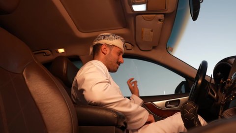الالتزام بوضع حزام الأمان, مفهوم القيادة الآمنة, سائق عربي خليجي عماني يرتدي الدشداشة و العمامة يمسك المقود بيده و يقود السيارة بتعابير السعادة والسرور, خدمة النقل و التوصيل في سلطنة عمان