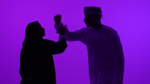 مفهوم الصراع الاسري، ازمة في العلاقات الزوجية، تصوير ظلي لرجل عربي خليجي عماني يرتدي الدشداشة والعمامة يتجادل مع زوجته بسبب سوء التفاهم، مشاكل عائلية وخلافات، الشجار بين الزوجين، خلفية بنفسجية، سالوييت