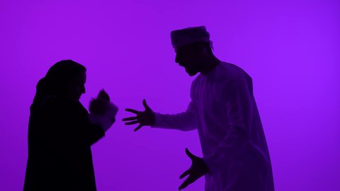 ازمة في العلاقات الزوجية، مفهوم الصراع الاسري، تصوير ظلي لرجل عربي خليجي عماني يرتدي الدشداشة والعمامة يتجادل مع زوجته بسبب سوء التفاهم، مشاكل عائلية وخلافات، الشجار بين الزوجين، خلفية بنفسجية، سالوييت