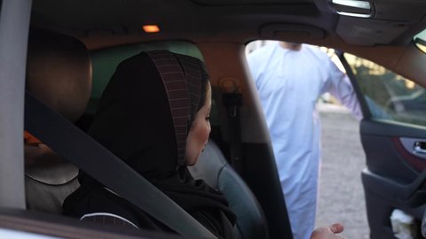 قضاء وقت ممتع مع الاسرة، ارتداء حزام الامان، رحله جماعيه عائليه في السياره، التنزه في شوارع سلطنه عمان مع العائلة، دردشه ومحادثات في الطريق، رجل عربي خليجي عماني يرتدي الدشداشة والعمامة يجلس مع زوجته داخل السياره، القيام بجولة ترفيهية بايماءات السعاده والسرور