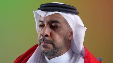 تشجيع الفريق المفضل، فوز المنتخب الوطني، إيماءات الاندماج والتفاعل ، رجل عربي خليجي كويتي يرتدي الثوب التقليدي يجلس على كرسي مريح يضع علم الكويت على كتفيه ، الشغف بمتابعة مباريات كرة القدم