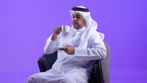 الاستمتاع والاحساس بالدفء ، الحيوية والنشاط عند شرب الكافيين، رجل عربي خليجي كويتي يرتدي الثوب التقليدي والغترة يحمل بيده كوب القهوة بتعابير السرور، رجل سعودي يستمتع بشرب المشروبات الساخنة