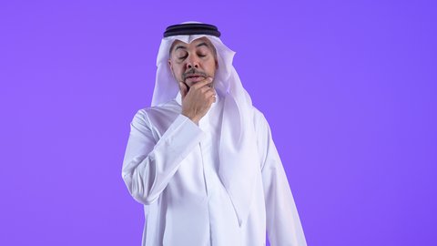 محاولة إيجاد حل للمشكلات الصعبة، القلق والحيرة في اتخاذ القرار الصحيح، التفكير بعمق وشرود الذهن، رجل عربي خليجي كويتي يرتدي الثوب التقليدي والغتره يضع يده أسفل ذقنه وينظر إلى الكاميرا ، رجل سعودي يقف بإيماءات الاندماج
