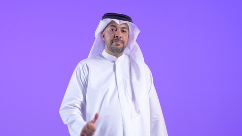 Expressing quality and craftsmanship, cheerfulness, and a sense of happiness, a smiling Kuwaiti Gulf Arab man wearing a traditional thobe and ghutra raises his finger in a gesture of quality, excellence, and distinction. A Saudi man gestures with a gesture of satisfaction and approval.