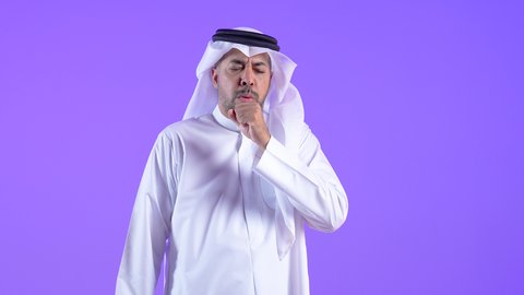 الكحة والتهاب الحلق، الحاجة لزيارة الطبيب وأخذ العلاج المناسب، إيماءات الإرهاق والتعب الشديد، رجل سعودي مصاب بالأنفلونزا ونزلات البرد، رجل عربي خليجي كويتي يرتدي الغترة والثوب التقليدي يضع يده أمام فمه ويقوم بالسعال