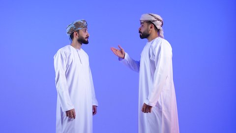 محاولة ضبط النفس وكتم الغضب, بورتريه لشاب عربي خليجي عماني يرتدي الدشداشة و العمامة  يرفع يديه و يتناقش بانزعاج لصديقة لطلب التوقف عن فعل الأخطاء, إيماءات العتاب والتوبيخ والرفض, خلفية زرقاء