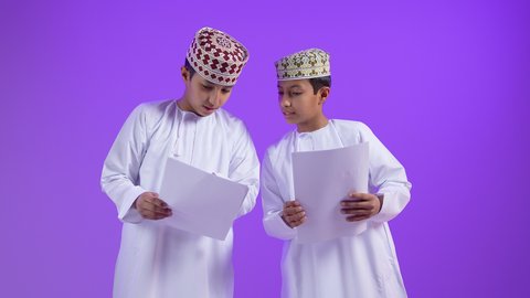 دراسة وواجبات منزلية، التعلم الفعال والمشاركة مع الطلاب, بورتريه  لطفل عربي خليجي عماني يرتدي الدشداشة و الكمة يحمل بيده مجموعة من الأوراق برفقة توأمة, طرائق تدريس حديثة، خلفية بنفسجية