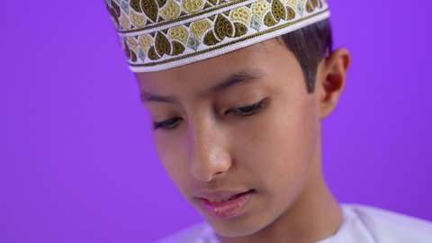 التعلم الفعال والمشاركة مع الطلاب, بورتريه مقرب لطفل عربي خليجي عماني يرتدي الدشداشة و الكمة  يحمل بيده مجموعة من الأوراق برفقة توأمة, دراسة وواجبات منزلية, طرائق تدريس حديثة، خلفية بنفسجية