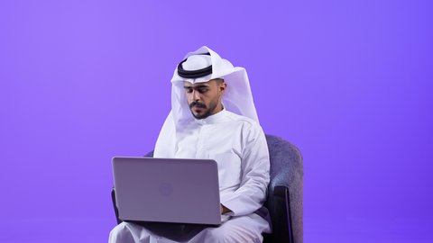 Focus, dedication, and hard work are employed in Kuwaiti offices and companies. A Kuwaiti Gulf Arab man wearing a traditional thobe and ghutra sits at a desk working on a laptop. A Saudi employee uses modern technologies in administrative and office work.