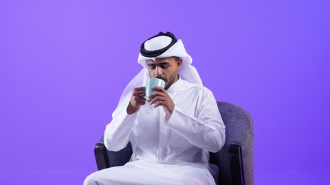 الاستمتاع والاحساس بالدفء ، الحيوية والنشاط عند شرب الكافيين، رجل عربي خليجي كويتي يرتدي الثوب التقليدي والغترة يحمل بيده كوب القهوة بتعابير السرور، رجل سعودي يستمتع بشرب المشروبات الساخنة
