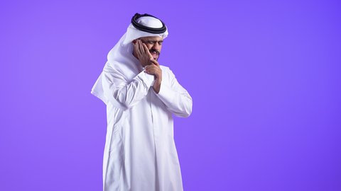 إلتهاب اللثه و تسوس الأضراس، طلب العلاج والمساعده، شاب عربي خليجي كويتي يرتدي الثوب التقليدي والغترة يضع يده على خده بإيماءات تدل على الشعور بألم الأسنان، رجل سعودي يحتاج لزيارة الطبيب