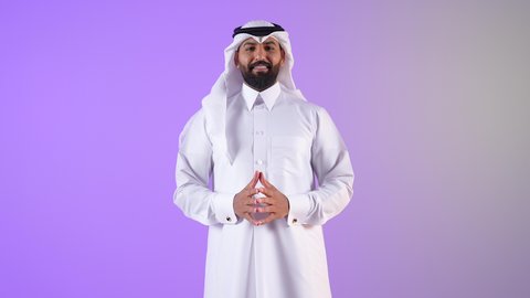 الوقوف باستعداد واستقامة، بورتريه لشاب عربي خليجي قطري يرتدي الثوب التقليدي والغترة ينظر الى الكاميرا بتعابير البشاشة، شاب سعودي يهتم بالاناقة و المظهرالخارجي، مفهوم الرجولة والثقة بالنفس،خلفية بنفسجية
