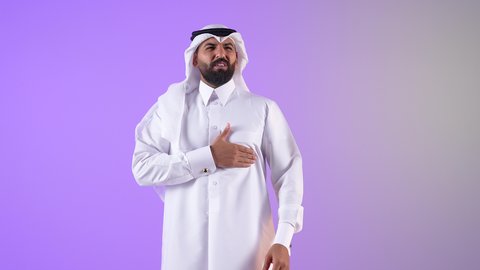 الذبحه الصدريه حالة مرضية، شاب سعودي يشعربالتعب والإرهاق والضغوطات النفسية، بورتريه لشاب عربي سعودي قطري يرتدي الغترة و الثوب التقليدي يضع يده على قلبه يشعر بحالة سيئة من الوخز والألم في قلبه, خلفية بنفسجية