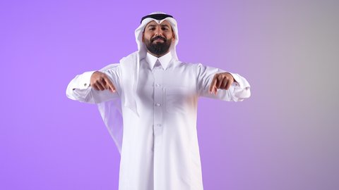 تأكيد حدوث شيء هذه اللحظة, حركات تدل على هذا المكان (هنا)، شاب سعودي يقوم بتحديد موقع معين، بورتريه لرجل عربي خليجي قطري يرتدي الثوب التقليدي والغترة يشير بإصابع السبابة نحو الأسفل, النظر إلى الكاميرا بايماءات السرور، خلفية بنفسجية