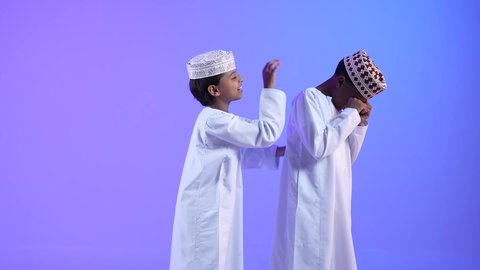 مفهوم التشجيع والمساعدة، صديق يواسي صديقه الحزين،ولد عربي خليجي عماني يرتدي الدشداشة والكمه يقوم بتقديم الدعم والمساندة لصديقه، تعابير محاولة التهدئة