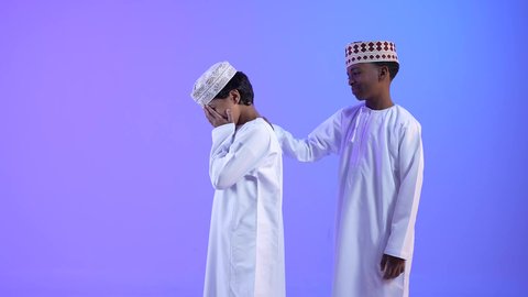 صديق يواسي صديقه الحزين، مفهوم التشجيع والمساعدة، ولد عربي خليجي عماني يرتدي الدشداشة والكمه يقوم بتقديم الدعم والمساندة لصديقه، تعابير محاولة التهدئة