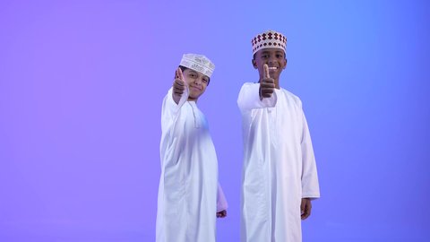 Welcoming, greeting, and saluting, building relationships and making new friends. Two Arab Gulf Omani friends wearing the dishdasha and the kama extend their hands to shake hands and greet each other. The greeting is greeted with a cheerful and welcoming face.