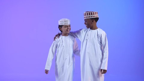 عناق واجتماع الاصدقاء، إيماءات وجه ويدين تدل على الحب والأمان، صديقان عربيان خليجيان عمانيان يرتديان الدشداشة والكمة احدهما يضع يده على كتف صديقة، حب والمساندة بين الاصدقاء