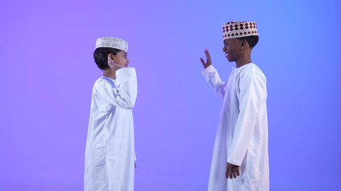 تكوين علاقات اجتماعية، صديقان عربيان خليجيان عمانيان يرتديان الدشداشة والكمة يتصافحان بحرارة،  مفهوم العلاقات المترابطة، ايماءات وجه ويدين تدل على السعادة، تعارف وصداقات ناجحة