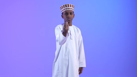 إمهال الوقت والإنتظار للقيام بشيء ما، ولد عربي خليجي عماني مبتسم يرتدي الدشداشة والكمة، يشير بإيماءات الصبر والتأن والتريث، الهدوء وطلب التوقف