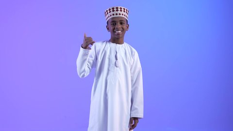 التواصل الإجتماعي عبر الجوال،  محادثات ودردشات و صداقات وتعارف, ولد عربي عماني خليجي يرتدي الدشداشة والكمة, إيماءات وجه ويدين تدل على إجراء مكالمه هاتفيه, طلب التواصل عبر الهاتف المحمول