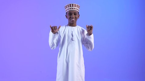 محادثات ودردشات و صداقات وتعارف, التواصل الإجتماعي عبر الجوال، ولد عربي عماني خليجي يرتدي الدشداشة والكمة, إيماءات وجه ويدين تدل على إجراء مكالمه هاتفيه, طلب التواصل عبر الهاتف المحمول