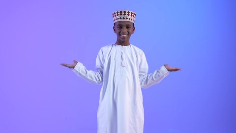 استخدام حاسة اللمس لتحريك العناصر الهولوجراميه، ولد عربي خليجي عماني مبتسم يرتدي الدشداشة والكمة يشير بيده بايماءات حمل ورفع شيء ما، الإشارة نحو هدف معين