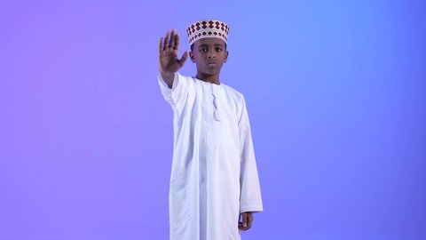 القلق والفشل في تحقيق أمر ما، تعابير عدم الموافقة، ولد عربي خليجي عماني يرتدي الدشداشة والكمة يشير بإصبع الابهام الى الاسفل بإيماءات الانزعاج والرفض