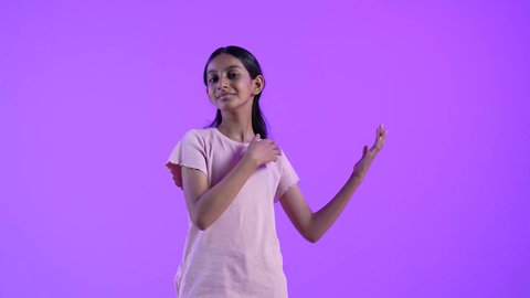 التوضيح والاشارة إلى شيء ما، بنت عربية خليجية عمانية ترتدي الزي الكاجوال وتشير بيدها إلى مكان ما، تحديد موقع معين بايماءات السعادة والسرور، إشارات وحركات يدين تدل على هذا المكان (هنا)