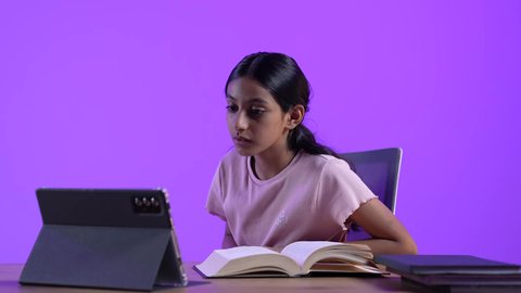 مراجعة الدروس اليومية عبر الانترنت، تطور العلم والتعليم في سلطنه عمان، طالبة عربية خليجية عمانية ترتدي الزي الكاجوال تجلس على طاولة امام جهاز التابلت المحمول تقوم بحل الواجبات المدرسيه وتلقي المحاضرات المدرسيه عن بعد