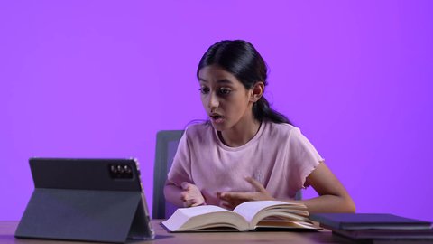 The development of science and education in the Sultanate of Oman, reviewing daily lessons online, an Arab Gulf Omani student wearing casual clothes sitting at a table in front of a portable tablet, solving school assignments and receiving school lectures remotely