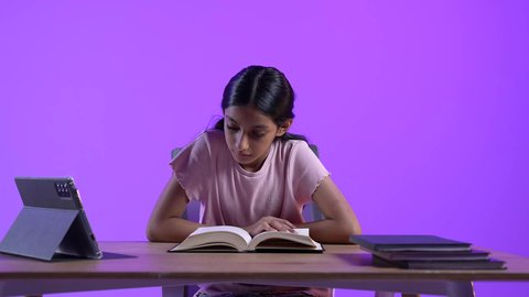 تطور العلم والتعليم في سلطنه عمان، طالبة عربية خليجية عمانية ترتدي الزي الكاجوال تجلس على طاولة امام جهاز التابلت المحمول تقوم بحل الواجبات المدرسيه ، مراجعة الدروس اليومية عبر الانترنت، تلقي المحاضرات المدرسيه عن بعد