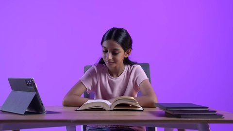 The concept of distance learning, the development of science and education in the Sultanate of Oman, an Arab Gulf Omani student wearing casual clothes sitting at a table in front of a portable tablet, solving school assignments, reviewing daily lessons online, and receiving school lectures remotely.