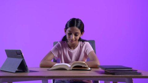 مراجعة الدروس اليومية عبر الانترنت، مفهوم التعلم عن بعد ، تطور العلم والتعليم في سلطنه عمان، طالبة عربية خليجية عمانية ترتدي الزي الكاجوال تجلس على طاولة امام جهاز التابلت المحمول تقوم بحل الواجبات المدرسيه ،  تلقي المحاضرات المدرسيه عن بعد