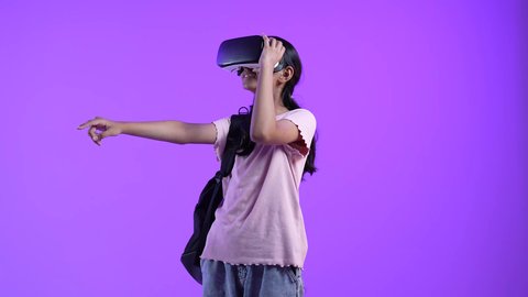 النظر والاشارة الى شئ ما ،دمج التقنيات الحديثة بالتعلم، محاكاة العالم الخيالي، طالبة عربية خليجية عمانية ترتدي حقيبة الظهر تضع نظارة الفي ار ثلاثية الأبعاد ،مفهوم التفاعل والاندماج