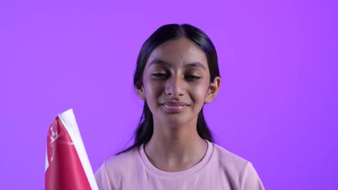 A close-up of an Omani Gulf Arab girl wearing casual clothes and an Omani flag with gestures of joy and happiness, commemorating Omani National Day, pride in Omani symbols, the concept of love of the homeland and belonging to it