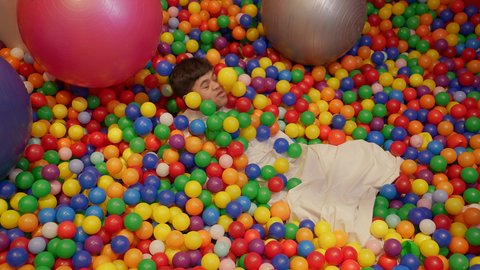 طفل سعودي مصاب بمتلازمة داون في مدينة الألعاب ، يلعب في حوض الكور البلاستيكية ، ايماءات السرور والسعادة، قضاء اوقات رائعة في مدينة الملاهي ،  الاستمتاع باللعب في العطلة الصيفية ، اوقات التسلية و الترفيه