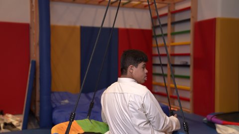 قضاء اوقات رائعة في مدينة الملاهي ،تصوير من الخلف لولد سعودي مصاب بمتلازمة داون في مدينة الألعاب ، يلعب لعبة المراجيح المسلية، الاستمتاع باللعب في العطلة الصيفية ، اوقات التسلية و الترفيه