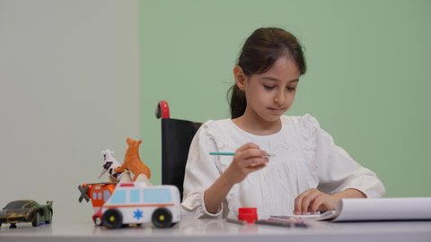 قضاء اوقات ممتعه، إيماءات التركيز والاستمتاع بالرسم و التلوين،تنمية المهارات الفنية في الروضات السعودية ، مفهوم الاهتمام بالهوايات, بنت عربية خليجية سعودية ترتدي الزي الكاجوال تقوم بالرسم والتلوين بالألوان