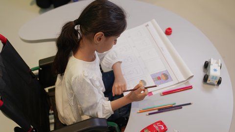 مفهوم الاهتمام بالهوايات, تنمية المهارات الفنية في الروضات السعودية ،إيماءات التركيز والاستمتاع بالرسم و التلوين، بنت عربية خليجية سعودية ترتدي الزي الكاجوال تقوم بالرسم والتلوين بالألوان ، قضاء اوقات ممتعه