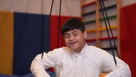 ايماءات السرور والسعاده ،  قضاء اوقات رائعة في مدينة الملاهي ،ولد سعودي مصاب بمتلازمة داون في مدينة الألعاب ، يلعب لعبة المراجيح المسلية، يشير بيده على شكل قلب ، الاستمتاع باللعب في العطلة الصيفية ، اوقات التسلية و الترفيه