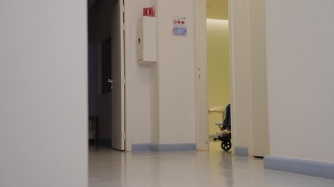 الرعاية الصحية والدعم النفسي للمرضى وذوي الاحتياجات الخاصة، امرأة عربية خليجية سعودية ترتدي العباءة السوداء تقوم بدفع فتاة صغيرة مبتسمة تجلس على كرسي متحرك  في المستشفى ، ايماءات العناية والاهتمام، بيئة طبية آمنة ، مفهوم الإنسانية والرحمة