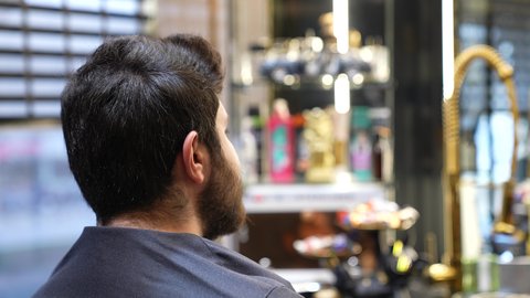 قص و تصفيف الذقن والشارب في صالون الحلاقة، تصوير مقرب لزبون عربي خليجي سعودي يجلس على الكرسي و يستعد للحلاقة،  المحافظة على الأناقة والنظافة الشخصية, تقديم خدمات العناية الشخصية