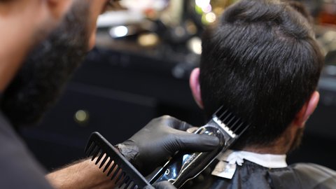 استخدام المشط و ماكينه الخلاقة, تقديم خدمات العناية الشخصية، ممارسة مهنه الحلاقة, تصوير مقرب ليد حلاق عربي خليجي سعودي يقوم بحلاقة شعر الزبون